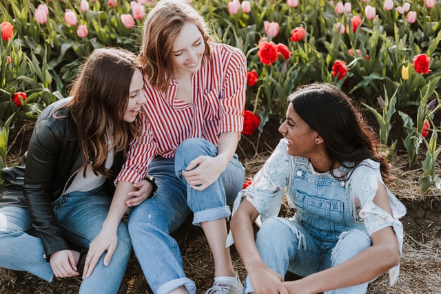 three girls hanging out in front of a field of tulips